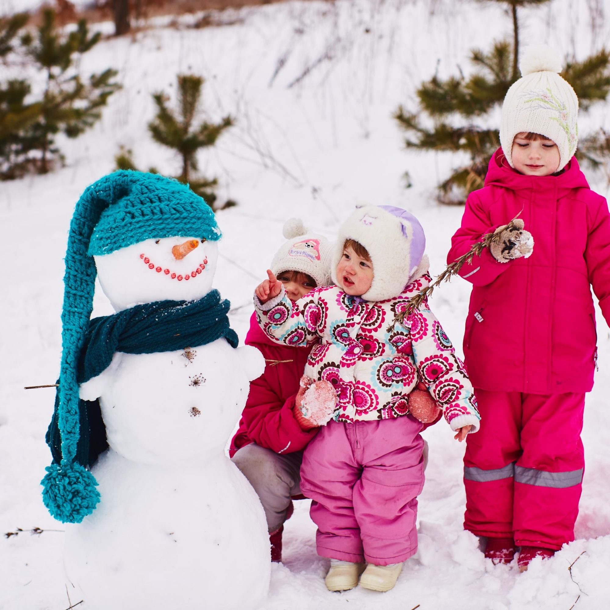 Little kids are looking at a beautiful snowman